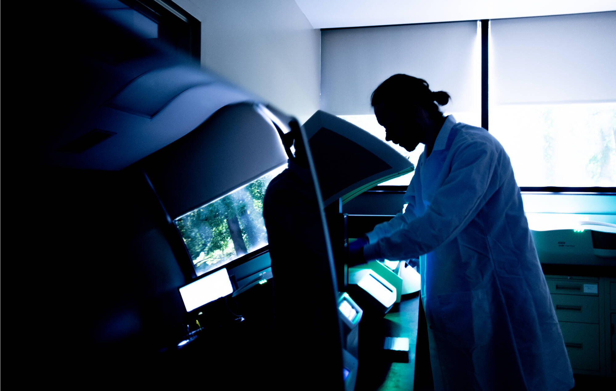 A person in a white lab coat working in a dark lab